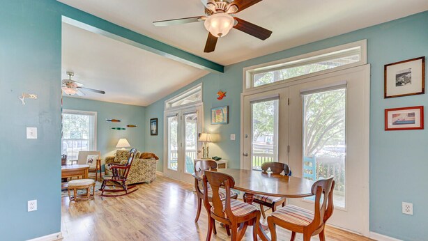 A spacious room with hardwood floors, a dining table with chairs, a rocking chair, and a ceiling fan. - SLW504A: Gone Coastal-Adorable 2 bed, 2 bath Unit Few Blocks from the Beach (Carolina Beach)