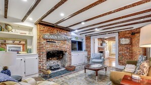 A cozy living room with a brick fireplace, a sofa, a coffee table, and a television.