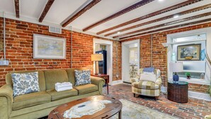 A cozy living room with a brick wall, a green sofa, a patterned armchair, and a round coffee table.
