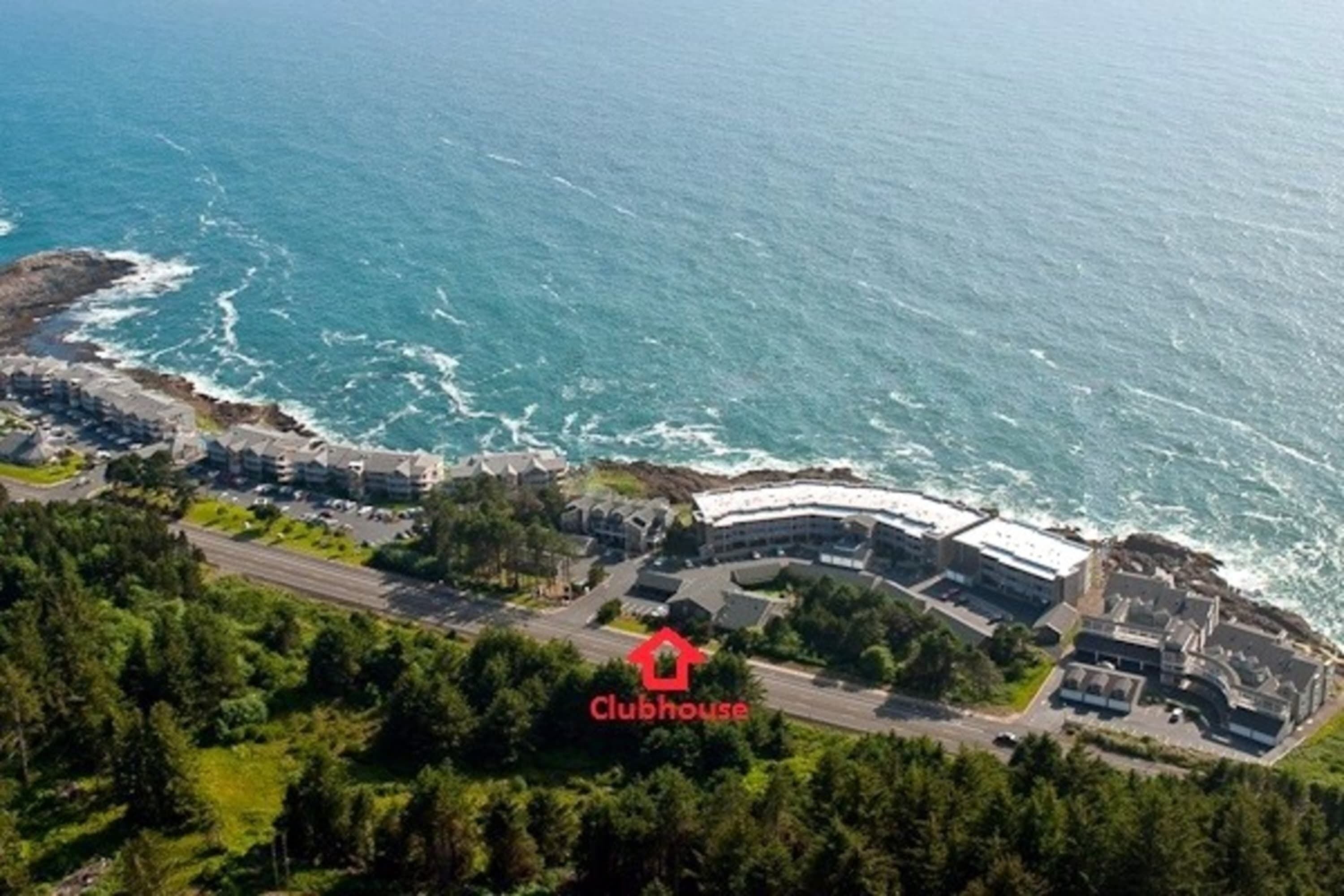 Vista aérea de un hotel costero con varias construcciones, un estacionamiento y vistas al océano.