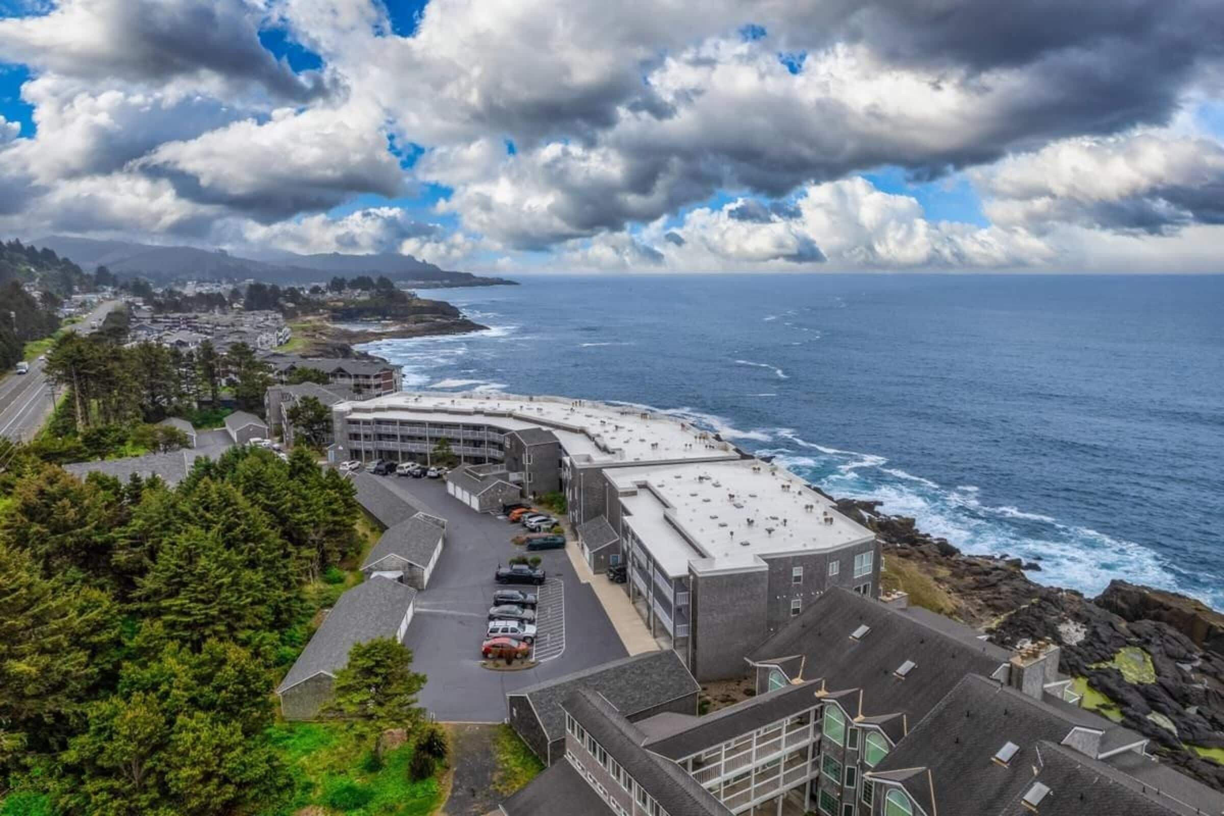 Hotel à beira-mar com construção curvilínea, área de estacionamento e vista para o oceano.