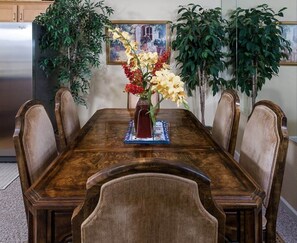 A dining table with a vase of flowers, surrounded by chairs.