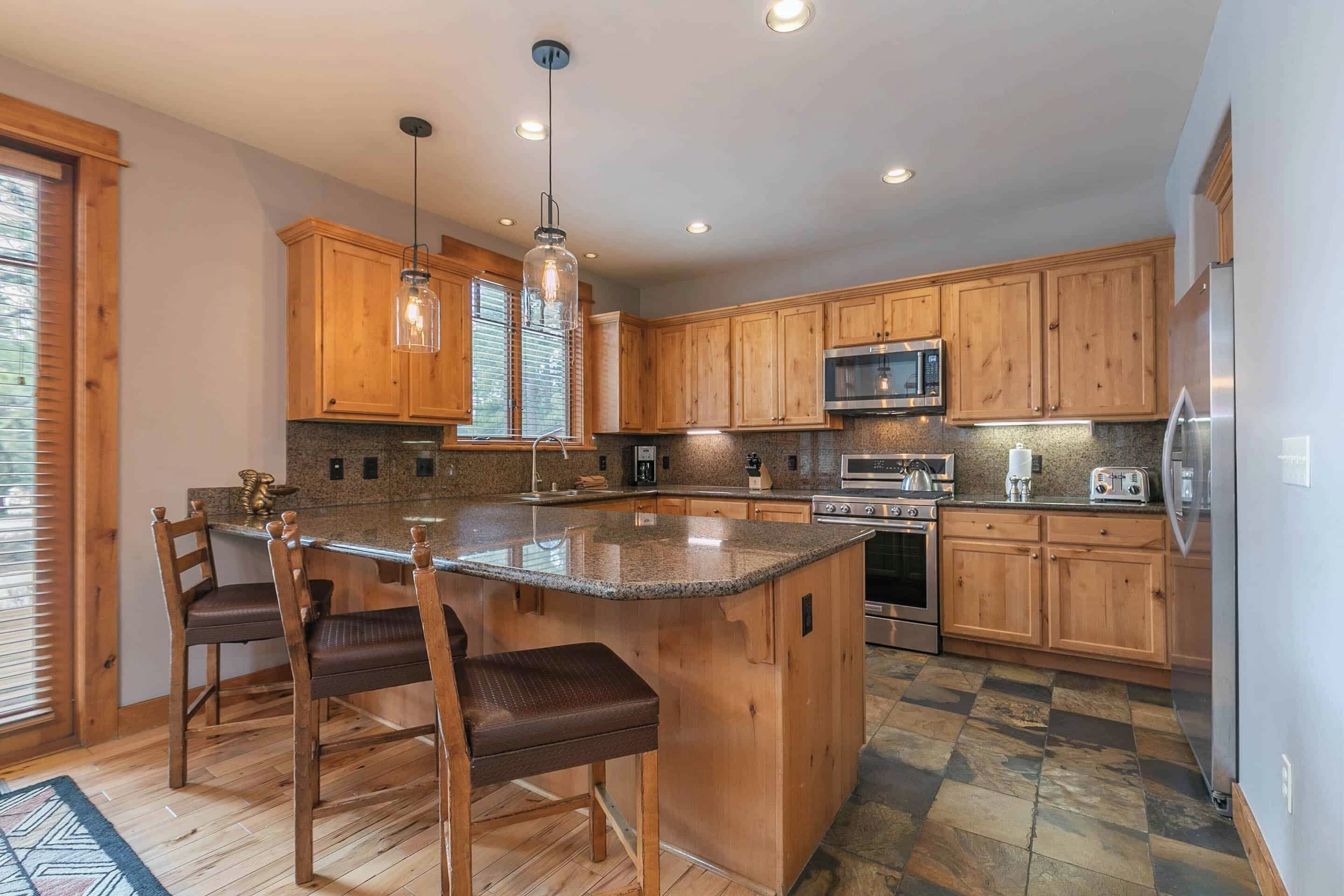 A spacious kitchen with wooden cabinets, a granite countertop, and modern appliances including a microwave and oven.