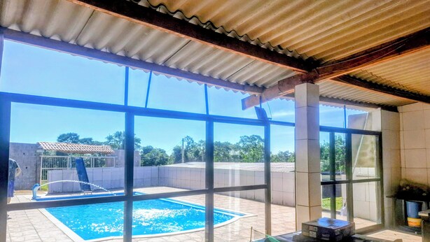 A pool area with a view of a building and trees. - Chacara Rancho da Cris (Ibiuna)