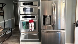 A kitchen with a built-in oven, a stainless steel refrigerator, and a microwave. - Great for families or corporate travelers. (Omaha)