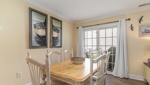 A dining area with a wooden table, white chairs, and two framed paintings on the wall. - 242 Georges Bay Road (Whole) located in Bermuda Bay. (Murrells Inlet)