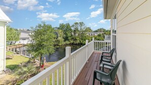 A balcony with a view of a river, surrounded by greenery and a white railing. - 242 Georges Bay Road (Whole) located in Bermuda Bay. (Murrells Inlet)