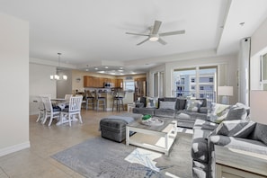 A spacious living area with a dining table, sofas, and a ceiling fan.