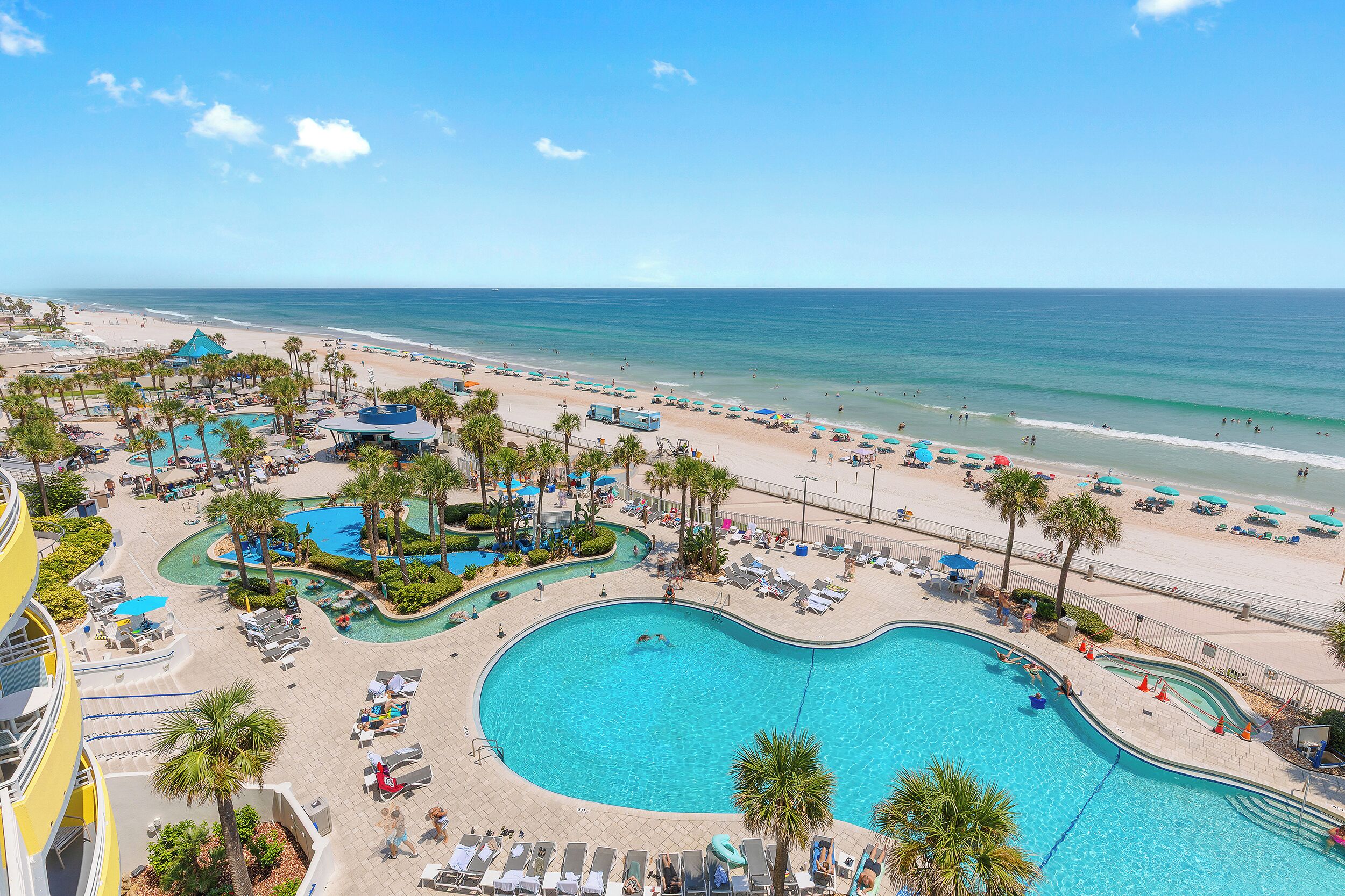 A resort with a large pool, beach, and ocean view.