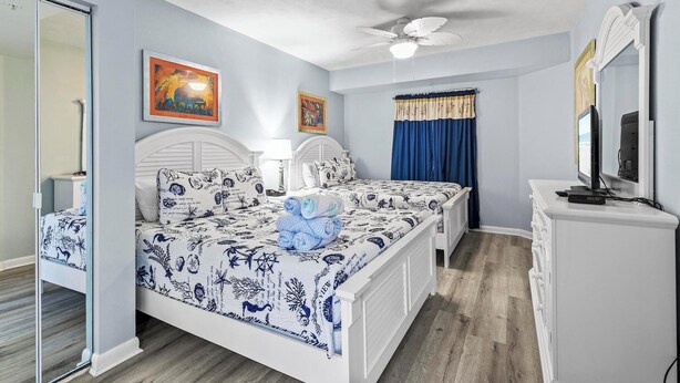 A bedroom with a bed, a dresser, a television, and a ceiling fan. - ☀️Ocean Front Condo with Expansive Views-Daytona Ocean Walk Resort 1707☀️ (Daytona Beach)