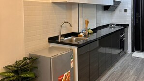 A modern kitchen with white cabinets, a black countertop, and a stainless steel refrigerator. - Alina Ridge (Nairobi)