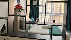 A modern bedroom with a bed, a vanity with a mirror, and a view of a cityscape through large windows. - Alina Ridge (Nairobi)