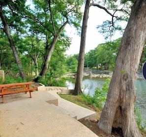 Un parc avec un banc en béton et un sentier en pierre menant à un plan d’eau.