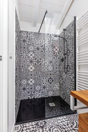 A shower with a black and white patterned tile wall and floor, a wooden bench, and a glass door. - Appartamento Guerrazzi by Wonderful Italy (Bologna)