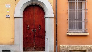 Um edifício com uma grande porta dupla de madeira, persianas verdes e uma pequena janela com grade de metal.