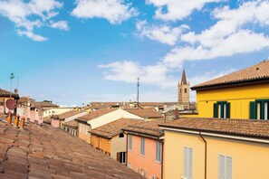 A view of a cityscape with terracotta-tiled roofs, a prominent church tower, and buildings with shutters. - Appartamento Guerrazzi by Wonderful Italy (Bologna)
