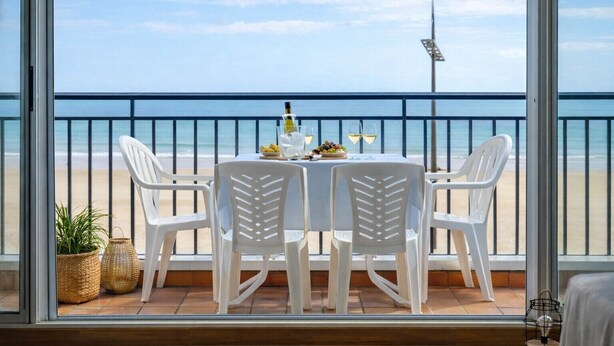 Ein Balkon mit Tisch für zwei Personen mit Blick auf einen Strand.