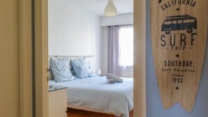 Ein Schlafzimmer mit einem Bett, einer Pendelleuchte und einer Wand mit einem Schild für eine Surf-Reise.