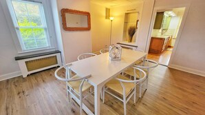 A dining area with a white table and chairs, a large mirror, and a view into the kitchen. - 10 Minutes to the beach! Historic home on the Jersey Shore. (Dennis)