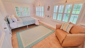 A bedroom with a bed, a sofa, and large windows. - 10 Minutes to the beach! Historic home on the Jersey Shore. (Dennis)