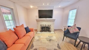 A living room with a sofa, a fireplace, a TV, and a window. - 10 Minutes to the beach! Historic home on the Jersey Shore. (Dennis)