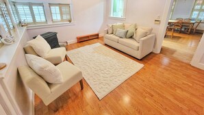 A spacious living room with a beige sofa, a matching armchair, and a patterned rug. - 10 Minutes to the beach! Historic home on the Jersey Shore. (Dennis)