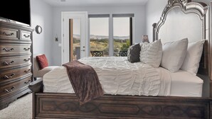 A bedroom with a large bed, a dresser, and a view of the outdoors. - Luxe 4BR w/ Canyon Views - 3 King Beds & Hot Tub (St. George)