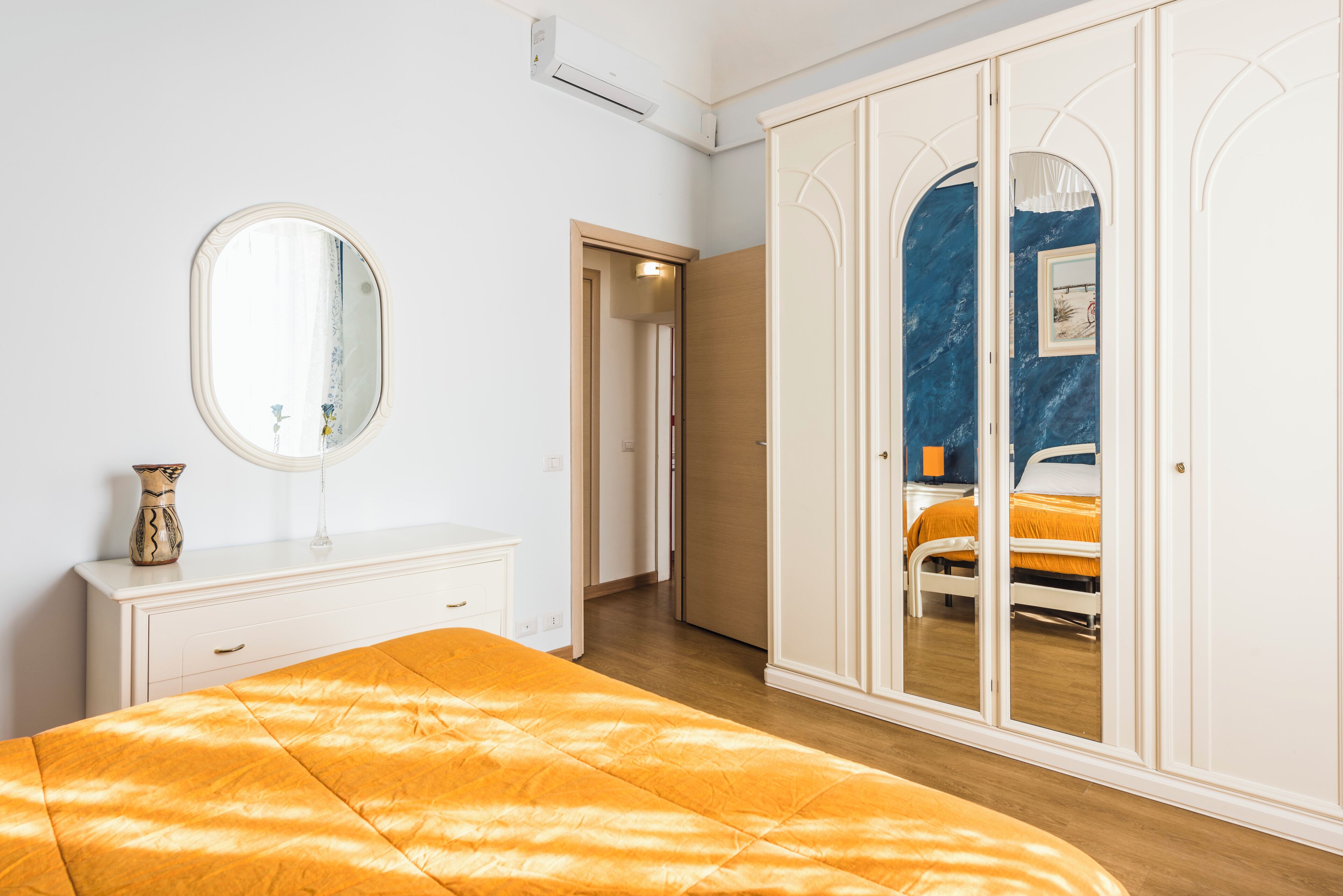 A bedroom with a bed, a dresser, a mirror, and a wardrobe.