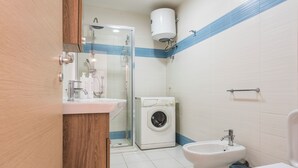 Ein Badezimmer mit Dusche, Waschmaschine, Bidet und Toilette.
