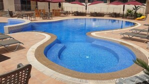 A swimming pool with a tiled edge, surrounded by lounge chairs and umbrellas. - Atlantis Akbou (Akbou)
