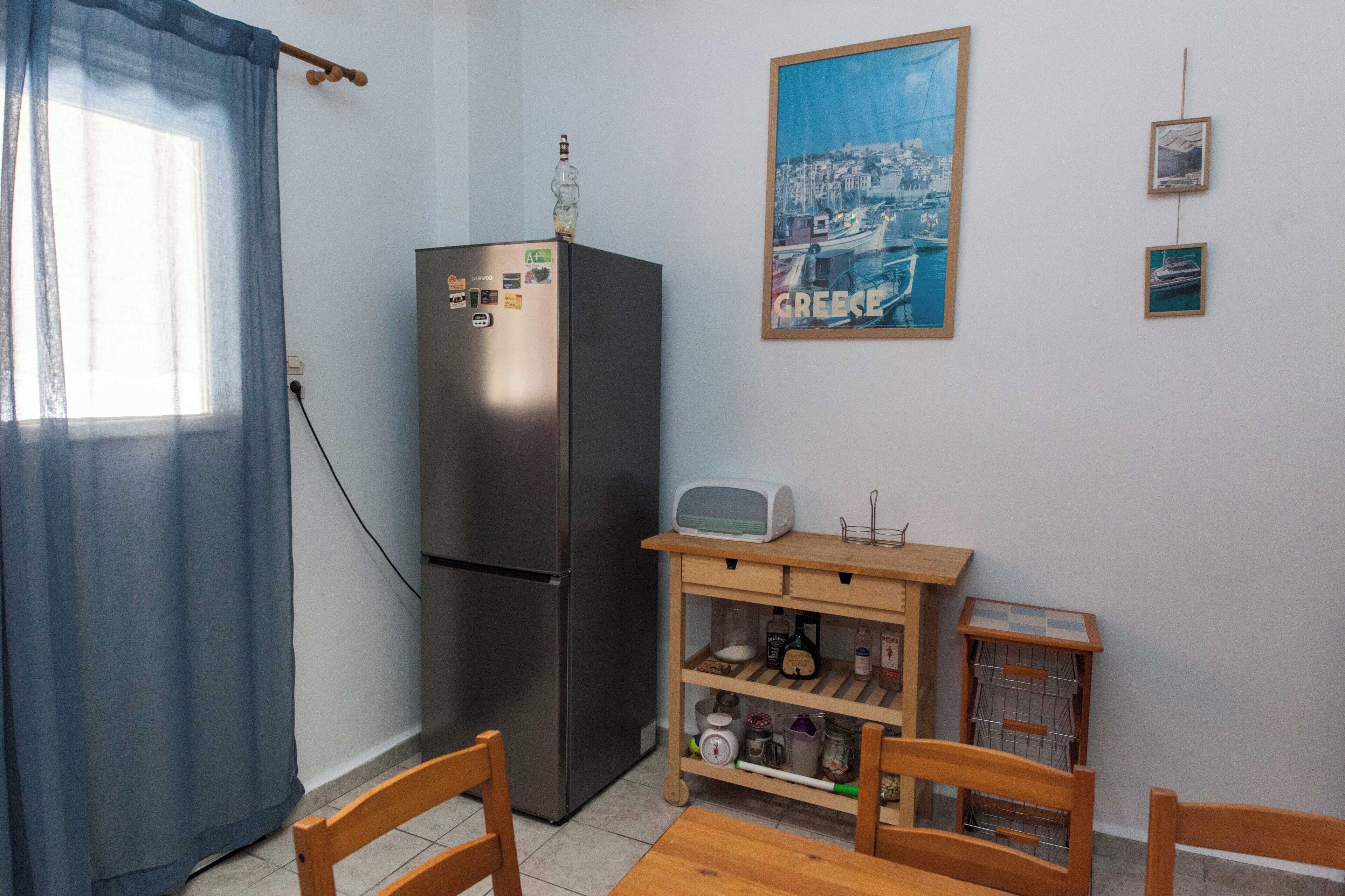 A compact kitchen with a refrigerator, microwave, and wooden table.