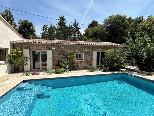 A stone house with a tiled roof, a swimming pool, and surrounding greenery. - Les Olicias – Provençal Villa with Private Pool and Panoramic Views (Flayosc)