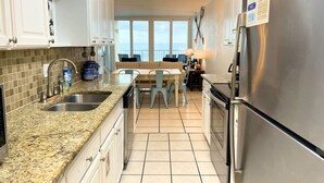 Una cocina con encimeras de granito, electrodomésticos de acero inoxidable, comedor con vistas y un balcón.