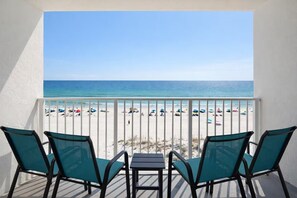 A balcony with a view of a beach, featuring a table and four chairs.