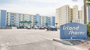 Un letrero de hotel que dice 'Island Shores 421' y un estacionamiento con varios coches.