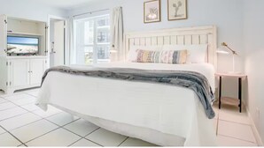 Un dormitorio con cama, mesita de noche, televisor y ventana con vistas.