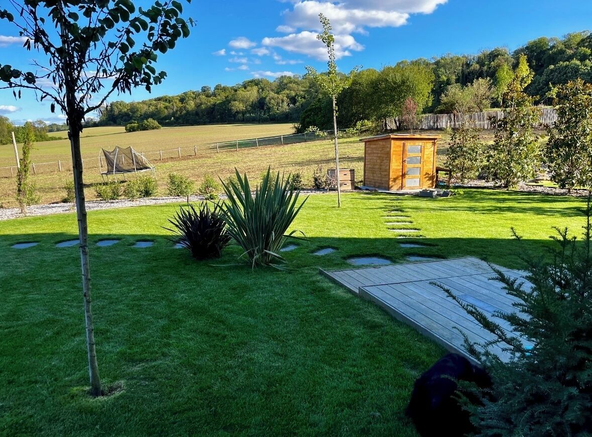 A well-maintained garden with a wooden deck, a small shed, and a fenced area.