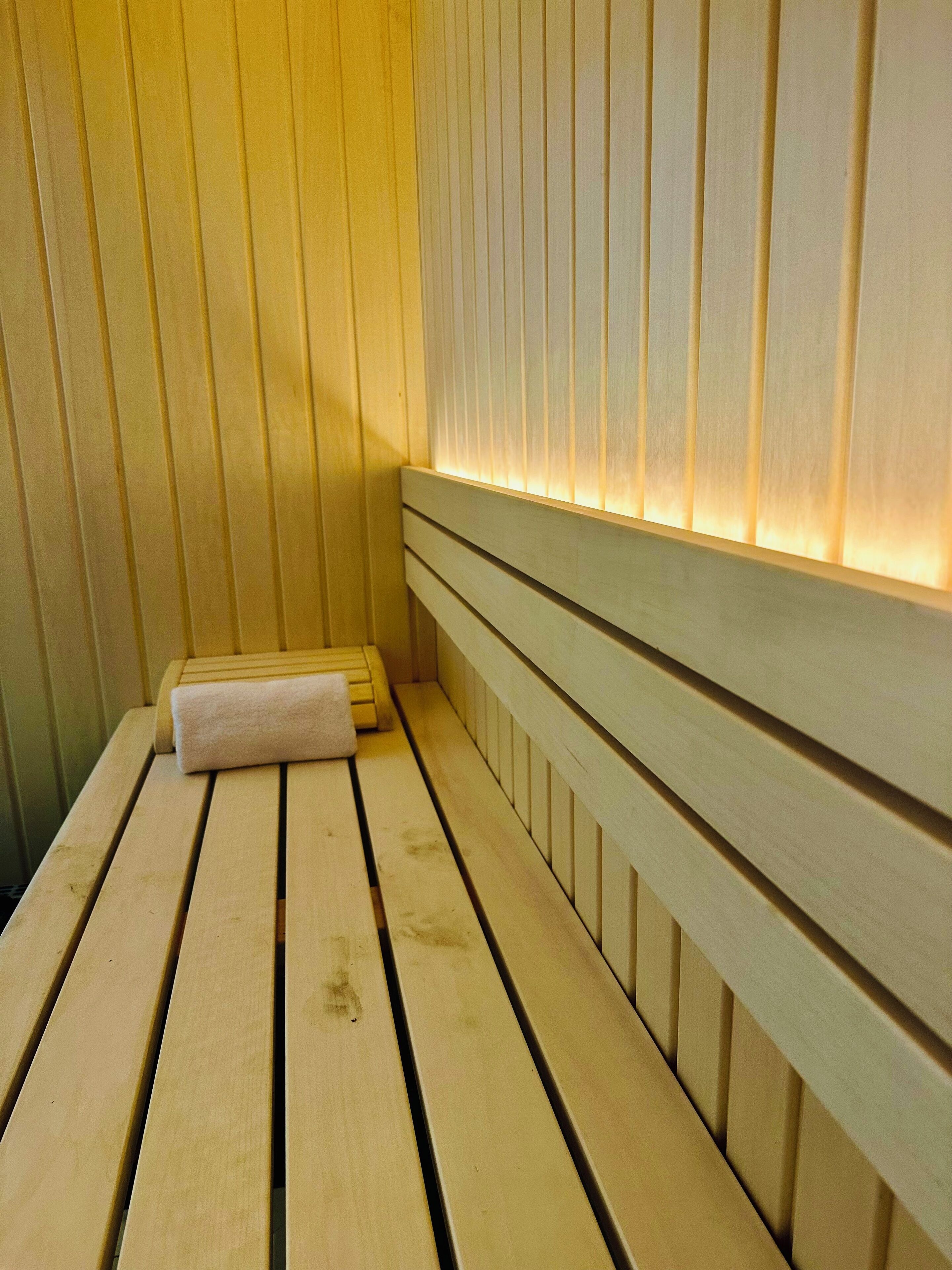 A wooden sauna bench with a towel, wooden walls, and a slatted ceiling.