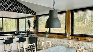 Eine moderne Küche mit einer großen Kochinsel, Barhocker und einem Esstisch mit Korbstühlen.