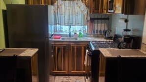 A compact kitchen with wooden cabinets, a gas stove, a microwave, and a sink.