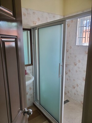 Un baño con ducha, lavamanos y espejo.