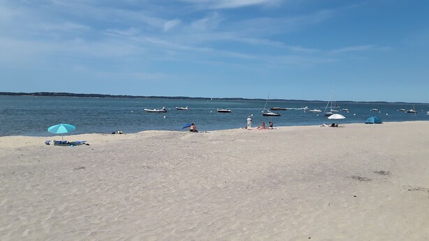 A beach with a sandy shore, a few umbrellas, and boats in the water. - Studio Accès Direct Plage (Arcachon)