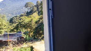 Una ventana con vistas a un paisaje montañoso, una pared con un cuadro enmarcado y una puerta parcialmente visible.
