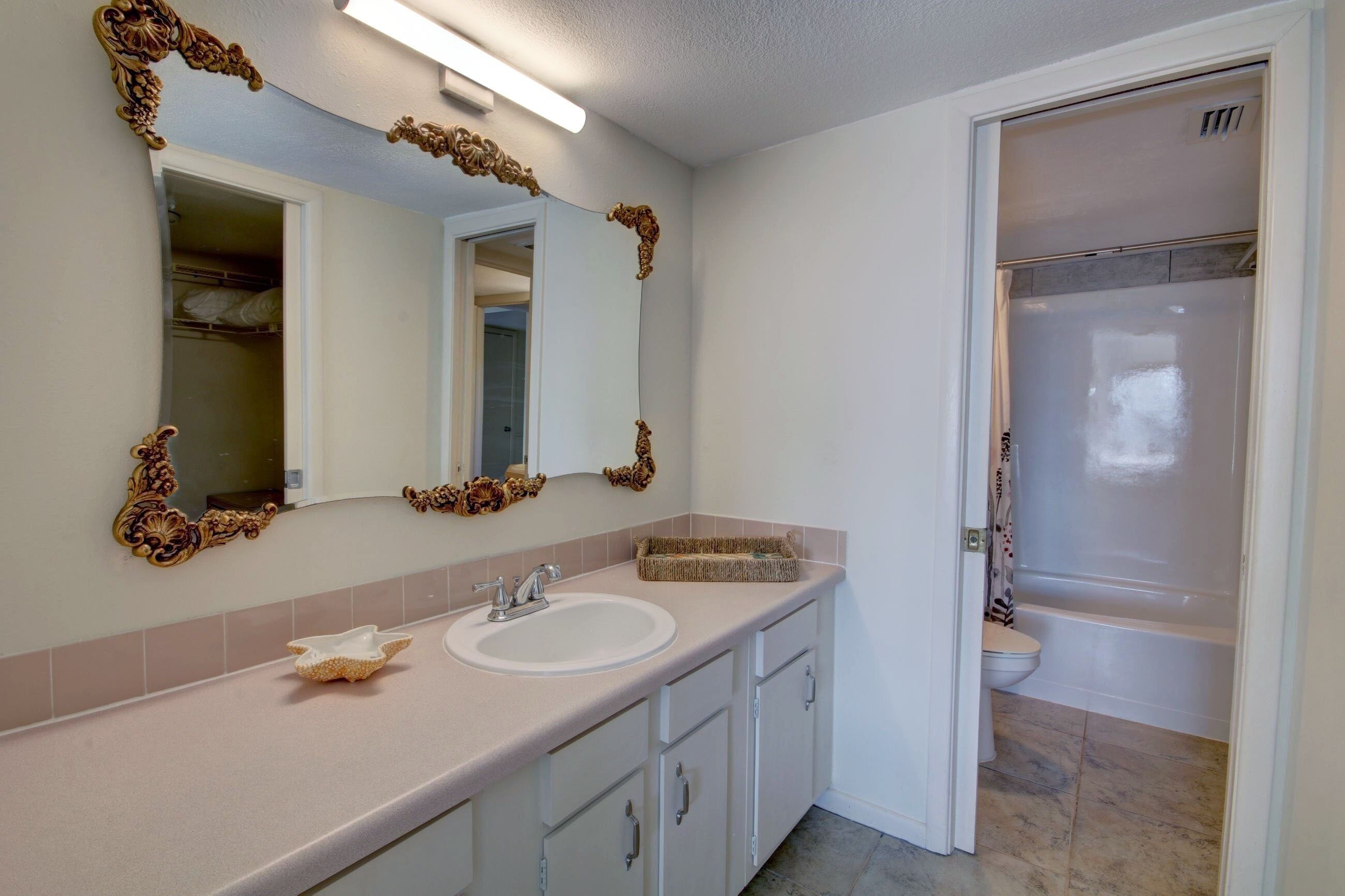 A bathroom with a white sink, vanity, and a shower.