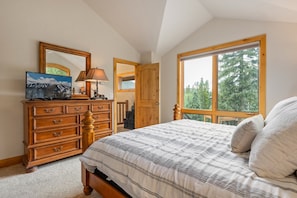 A bedroom with a bed, wooden dresser, and a large window with a view of trees. - 103 Antler Way At Lakota 4 Bedroom Townhouse by RedAwning (Winter Park)