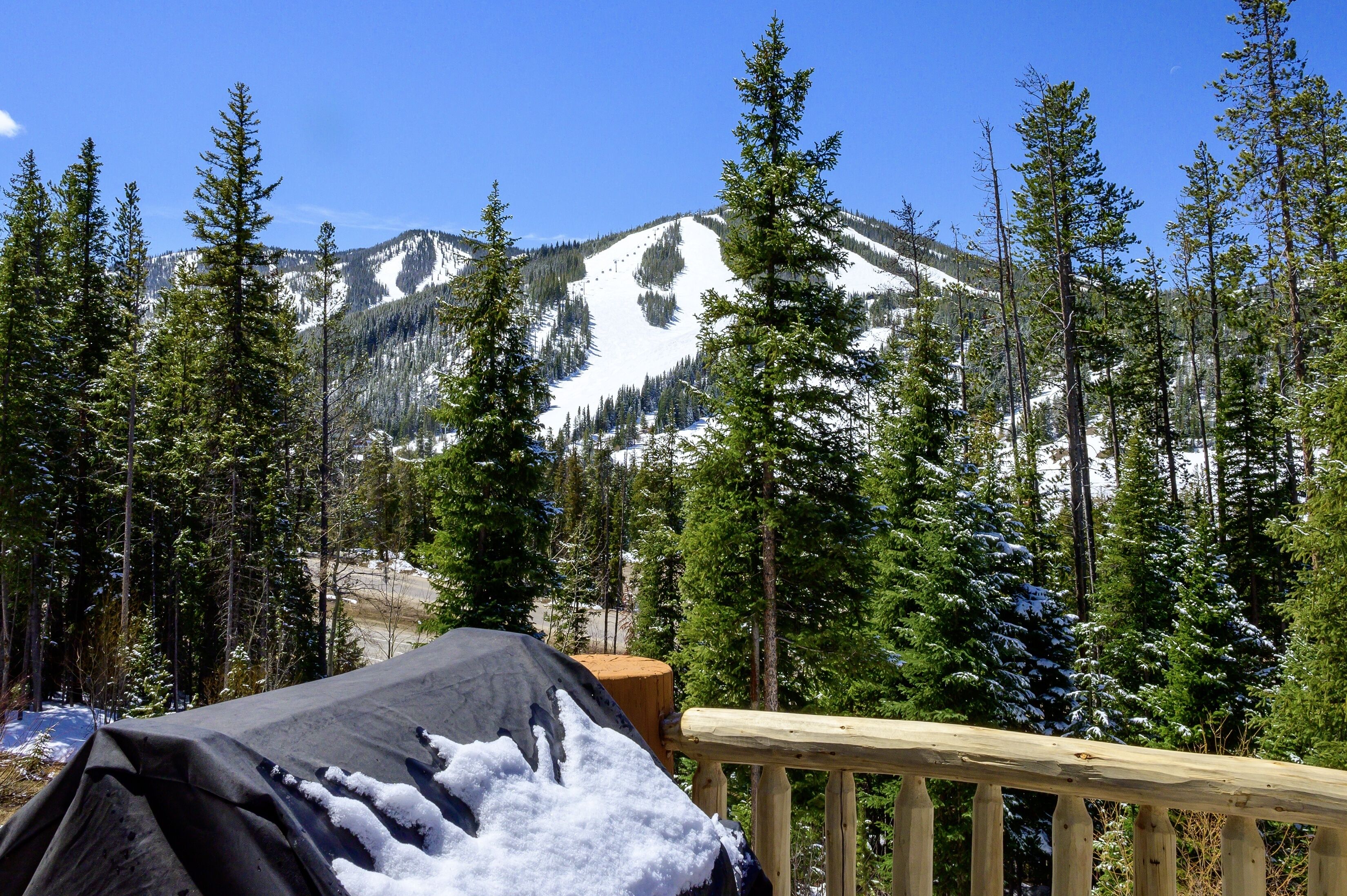 Eine Berghütte mit einer Holzterrasse und einem überdachten Sitzbereich im Freien.