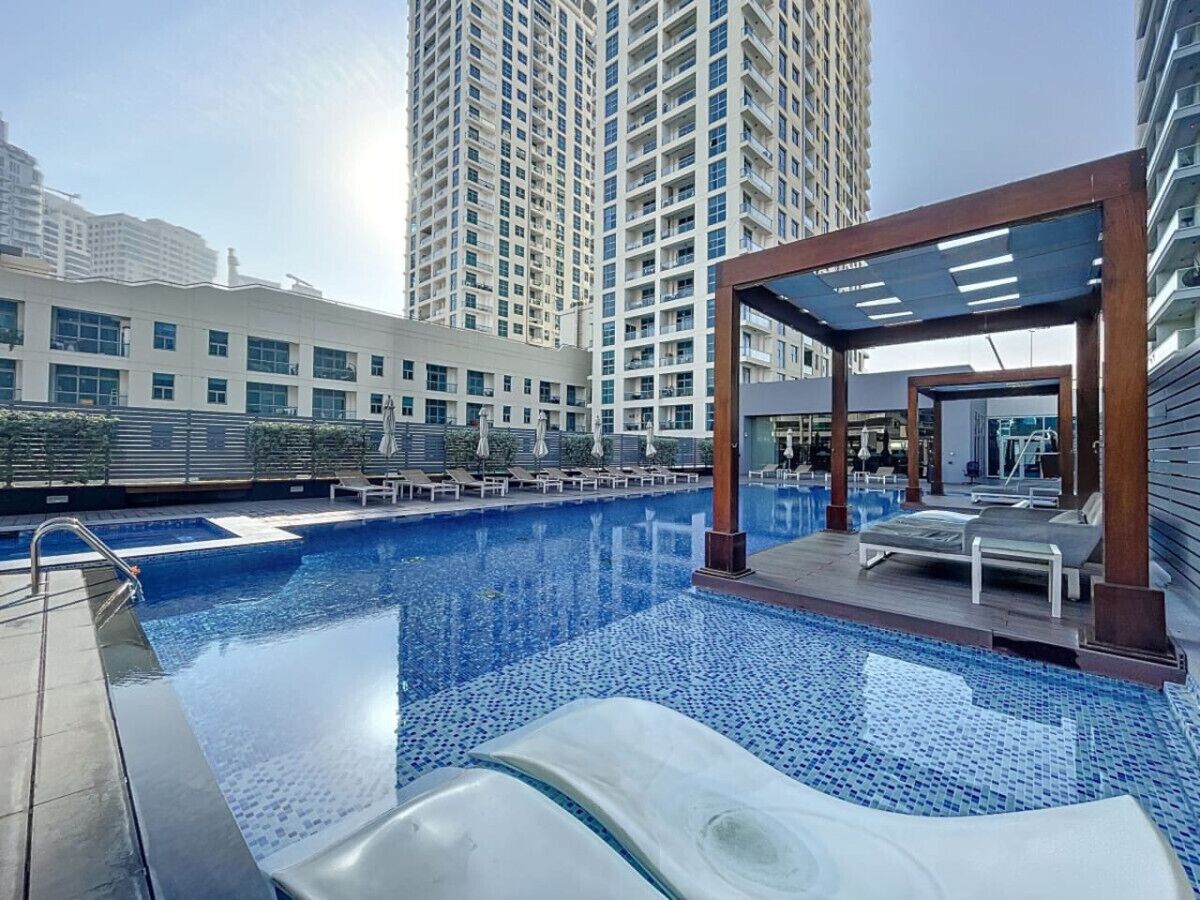 A rooftop swimming pool with lounge chairs and a covered seating area.