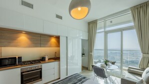 Una habitación de hotel moderna con cocina, zona de comedor y un amplio ventanal con vista a la ciudad.