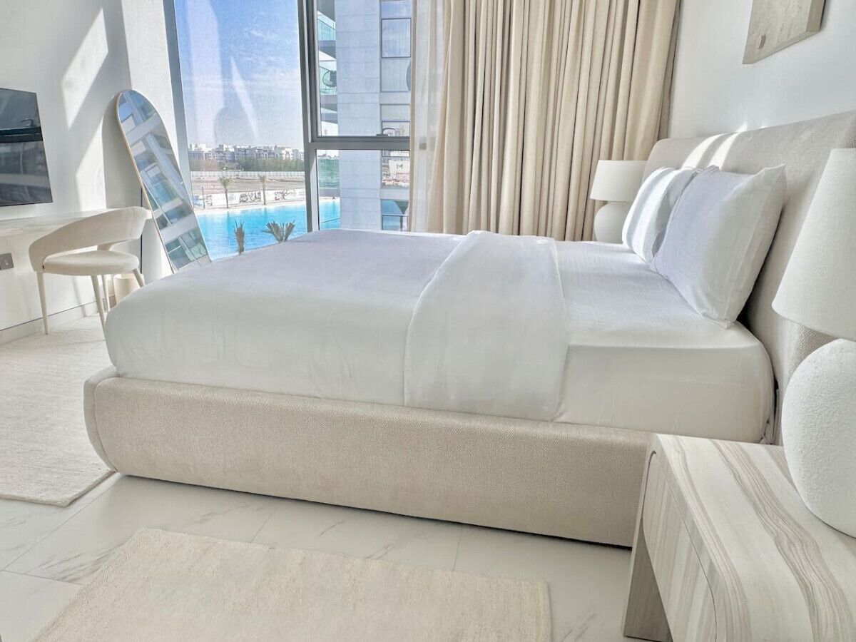 Een moderne slaapkamer met een groot bed, uitzicht op een zwembad en een stadsgezicht.