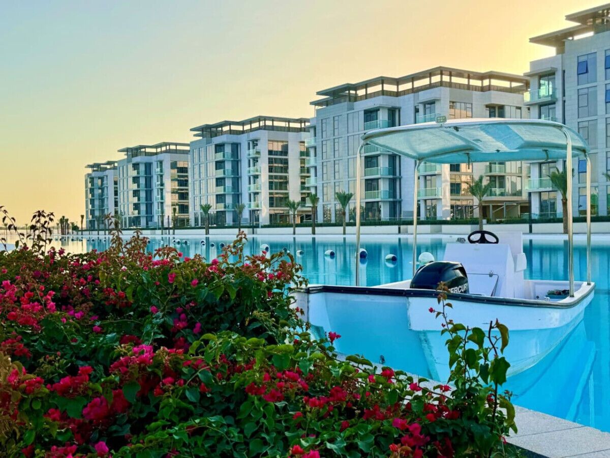 Un hôtel moderne doté d’une piscine, d’un bateau et d’une végétation luxuriante.